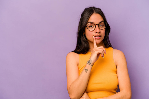 Young hispanic woman isolated on purple background looking sideways with doubtful and skeptical expression. - Photo, Image
