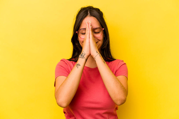 Mladá hispánka izolovaná na žlutém pozadí drží ruce v modlitbě blízko úst, cítí se sebejistě. - Fotografie, Obrázek