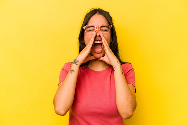 Young hispanic woman isolated on yellow background shouting excited to front. - Photo, image