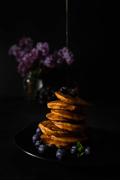 Homemade pancakes with maple syrup and fresh blueberries. Homemade and healthy breakfast with dark background. Gluten free carrot pancakes - Photo, image