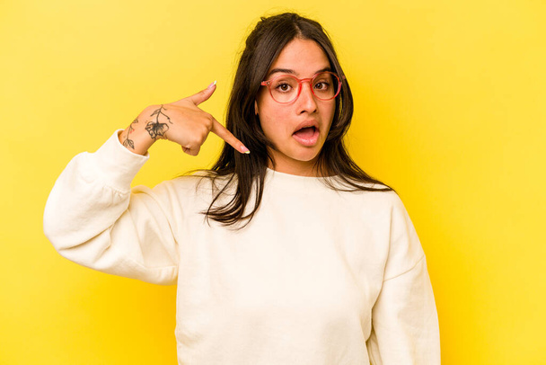 Nuori latino nainen eristetty keltainen tausta henkilö osoittaa käsin paita kopioi tilaa, ylpeä ja luottavainen - Valokuva, kuva