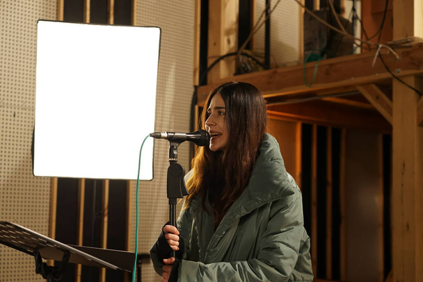 Дівчина співає в мікрофон для запису вокалу
 - Фото, зображення