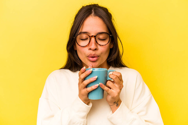 Young hispanic woman holding a mug isolated on yellow background - Fotoğraf, Görsel