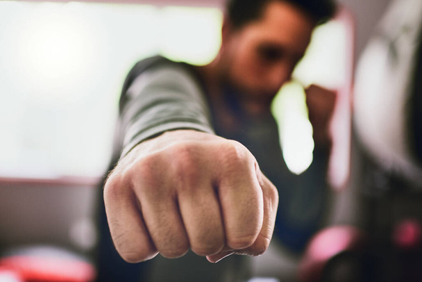 Time to put these guys to work. Closeup of a focused young male boxer throwing punches at the camera inside of a ring at a gym during the day. - Fotoğraf, Görsel