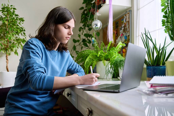 Teenage male student studying at home using a laptop - Φωτογραφία, εικόνα