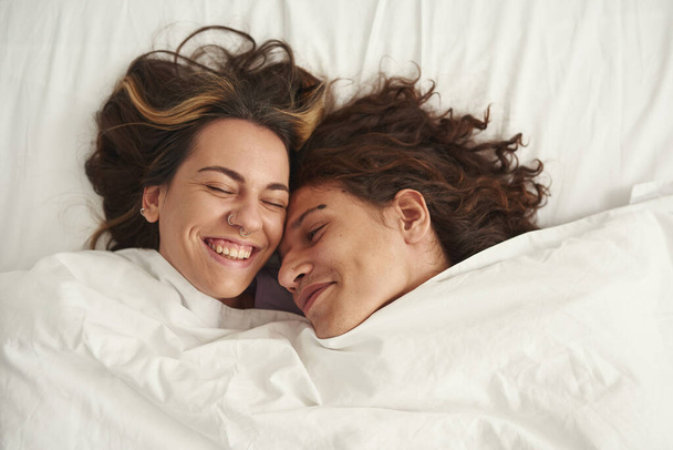 Top view of happy couple lay under blanket on bed - Foto, imagen