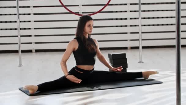 Gymnastiektraining - jonge vrouw zittend in de split en strekkend op de vloer - Video