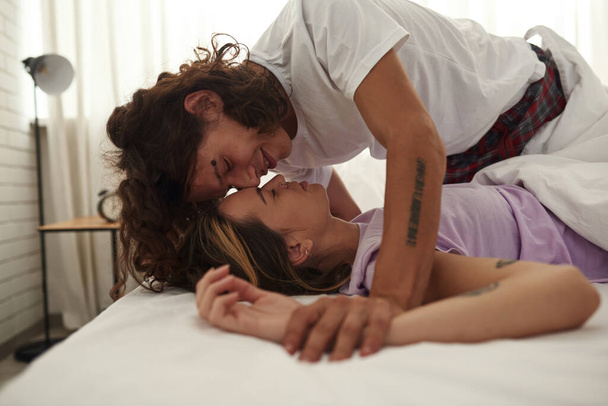 Young couple touching each other on bed at home - Фото, зображення