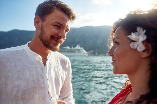 Portrait shot of young couple looking at each other. Cruiser and mountains in background. Togetherness, lifestyle, love, holiday concept. - Zdjęcie, obraz