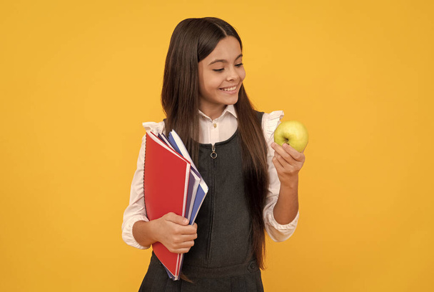 おやつの時間だ。幸せな女の子は、リンゴを保持する学校の本を見て。学校のおやつだ。食教育 - 写真・画像