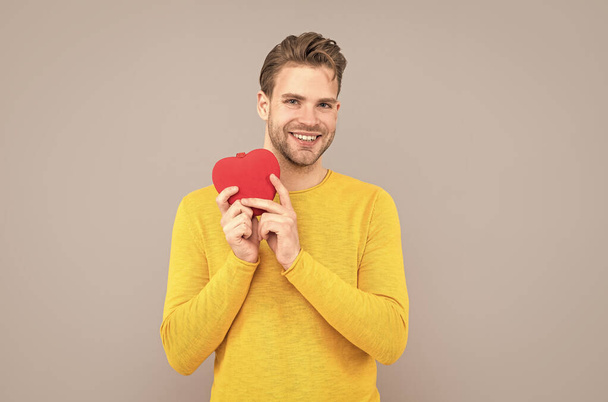 gelukkig jongeman glimlach holding valentines hart grijs achtergrond, liefde - Foto, afbeelding