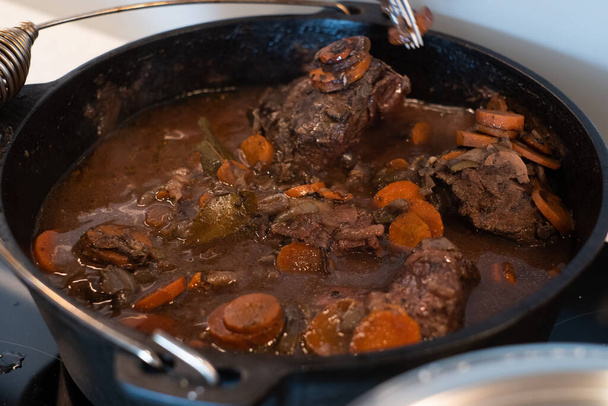 Braised beef cheeks cooking in red wine sauce in cast iron Dutch oven. - Foto, Imagem