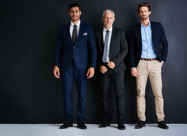 Третє це чарівне число для успіху. Студійний портрет трьох бізнесменів, що стоять на чорному тлі
. - Фото, зображення