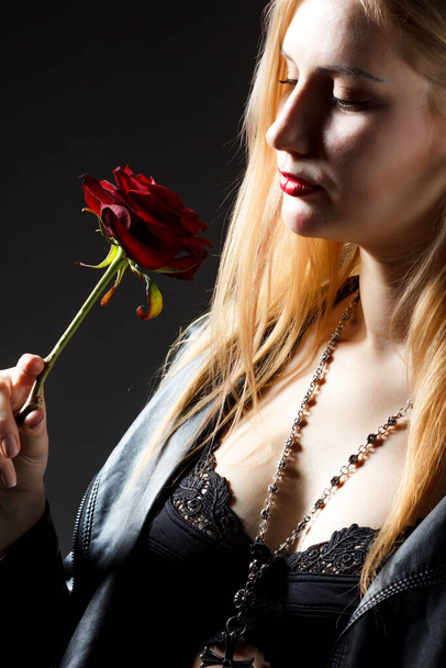 Beautiful happy girl holds red rose close to face and looks at camera. - Foto, Imagen