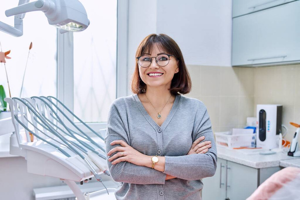 Portrait of smiling mature woman in dental clinic looking at camera - Foto, afbeelding