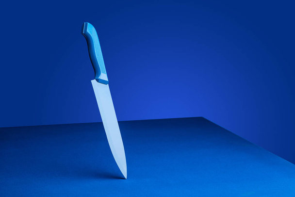 Blue knife on a blue background. The concept of minimalism - Photo, image
