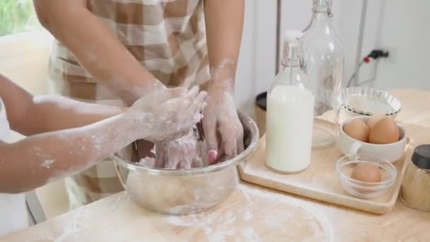 Closeup hands of mother wearing apron thresh flour for cooking and dancing with daughter together in the kitchen at home, parent and little child preparing food with fun and playful, family concept. - Metraje, vídeo