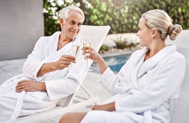 Heres to us and our special day. Shot of a cheerful middle aged couple having a celebratory toast with champagne outside during the day. - Foto, Imagem