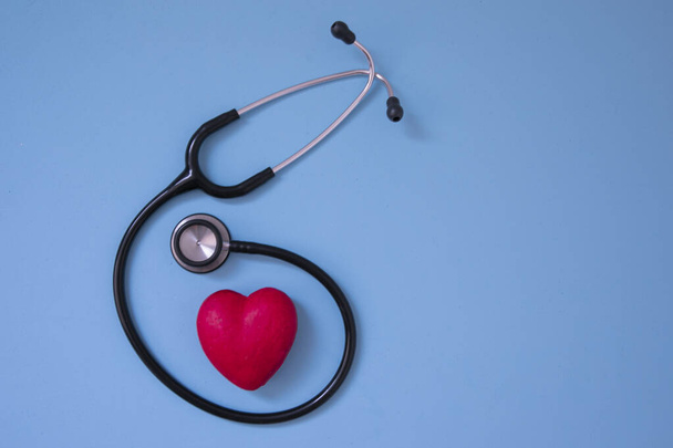 Red heart shape and medical stethoscope on blue background top view. Health care, medicare and cardiology concept. copy space. - Foto, Imagen