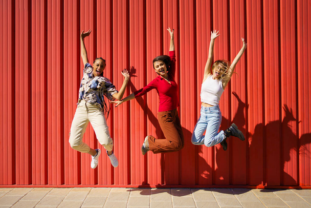 Excited multiethnic women jumping on street - Foto, Imagem