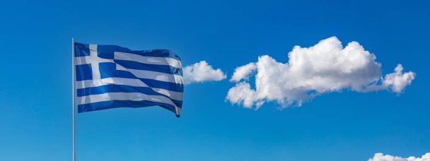 Rüzgarda dalgalanan bayrak direğindeki Yunan ulusal bayrağı. Yunanistan 'ın işareti. Bulutlu mavi gökyüzü, Atina 'da güneşli bir bahar günü. - Fotoğraf, Görsel