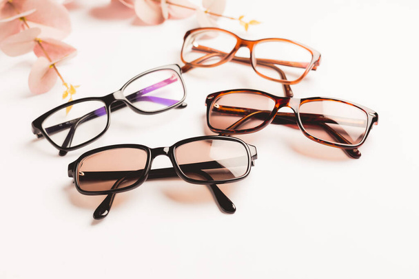 Varias gafas elegantes de moda sobre fondo blanco con espacio para copiar. Óptica, tienda de gafas y monturas concepto. - Foto, imagen