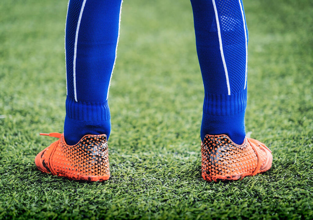 Kid footballer feet closed up on a green grass field for youth soccer training concept. - Foto, imagen