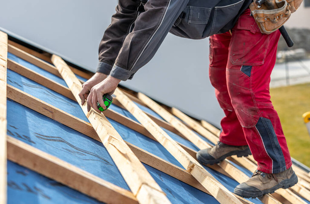 Handwerker oder Bauarbeiter montieren ein neues Dach, Dachwerkzeuge, neues Metalldach oder Blech, Baukonzept - Foto, Bild