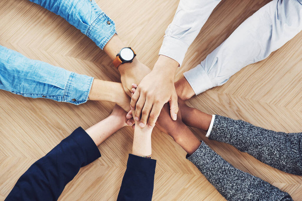 Its easier if we do it together. High angle shot of a group of unidentifiable businesspeople joining their hands together in unity. - Fotografie, Obrázek
