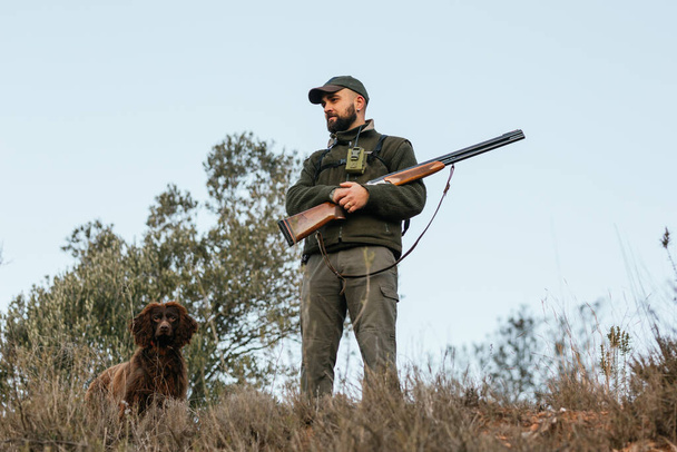 Metsästäjä seisoo katsoen pois koiransa kanssa vuorella - Valokuva, kuva