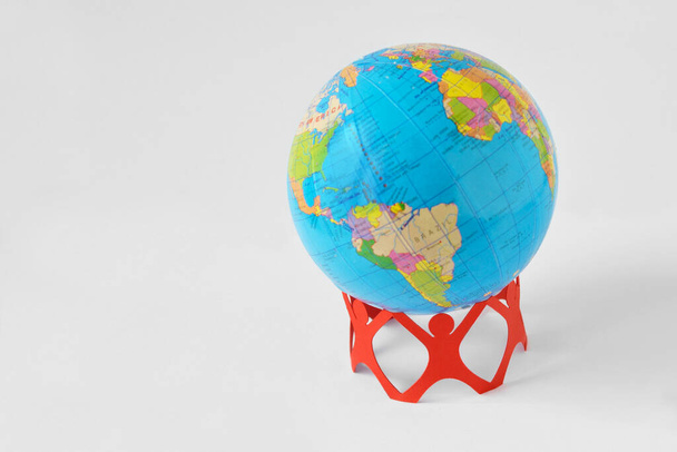 Yerküre küresini tutan kağıttan insanlar dünyayı kurtarır. - Fotoğraf, Görsel