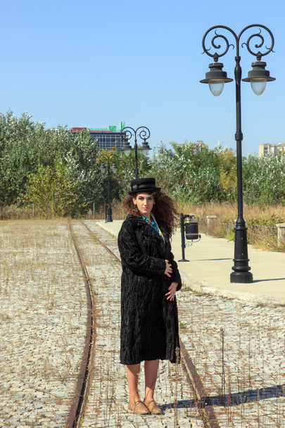 Frau mit lockigem Haar trägt Retro-Pelzmantel und Hut - Foto, Bild