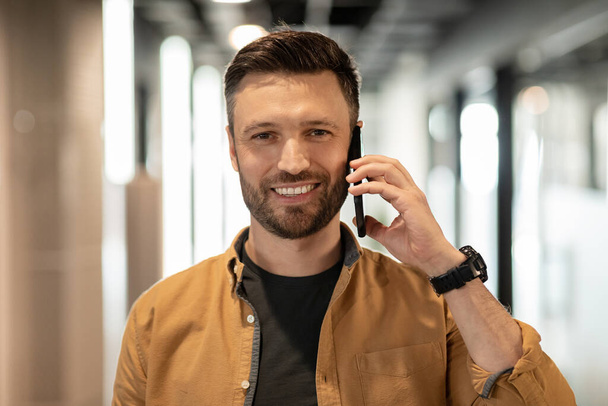 Щасливий бізнесмен розмовляє по телефону стоячи в двері в офісі
 - Фото, зображення