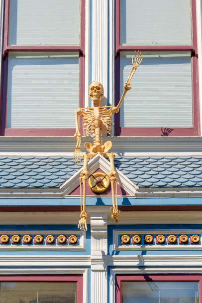 Skelett auf einem Dach mit u-förmigen Ziegeldächern in San Francisco, Kalifornien. Holloween-Dekor auf dem Dach eines Wohnhauses mit verzierten viktorianischen Zierleisten und gerahmten Fenstern. - Foto, Bild