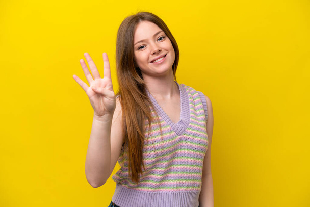 Fiatal kaukázusi nő elszigetelt sárga háttér boldog és számolás négy ujjal - Fotó, kép