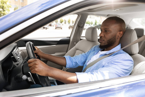 Itsevarma musta mies ajaa uutta autoa kaupungissa - Valokuva, kuva