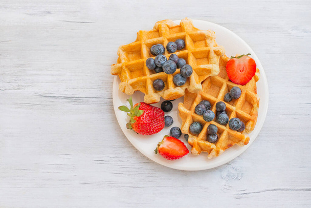 Homemade belgian waffles with  strawberries and blueberries. Delicious Breakfast with berries. - Fotó, kép
