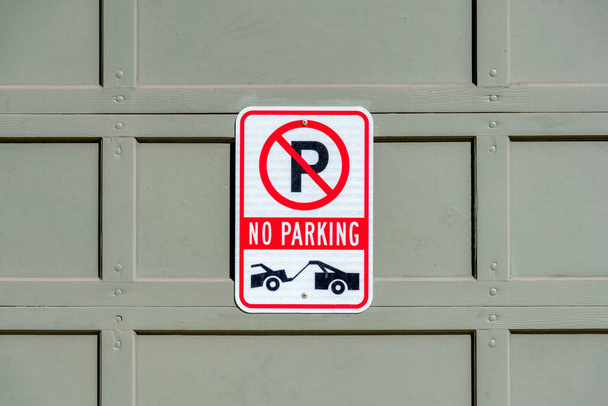 Kein Parkschild mit Abschleppwagen-Symbol in San Francisco, Kalifornien. Keine Parkplatzbeschilderung auf grauem getäfeltem Sektionalgaragentor. - Foto, Bild