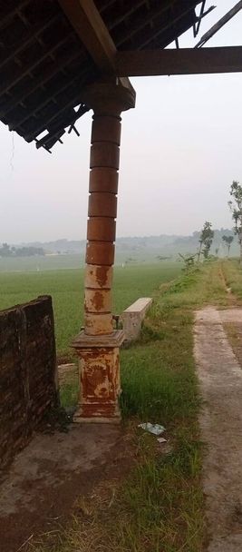column that has experienced deflection with foggy ricefield as a background landscape - Photo, Image