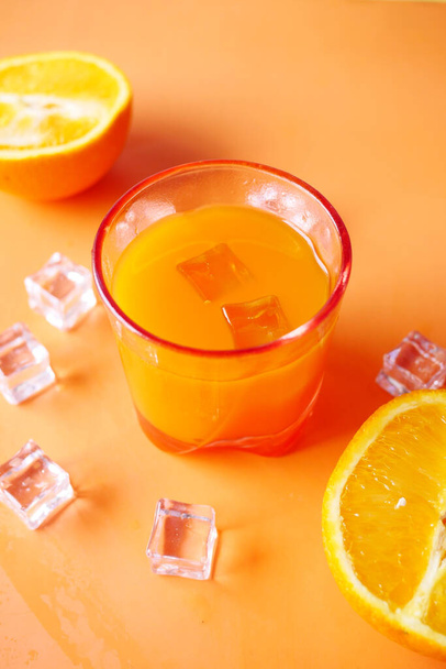 top view of a glass of orange juice with ice on color background  - Fotó, kép