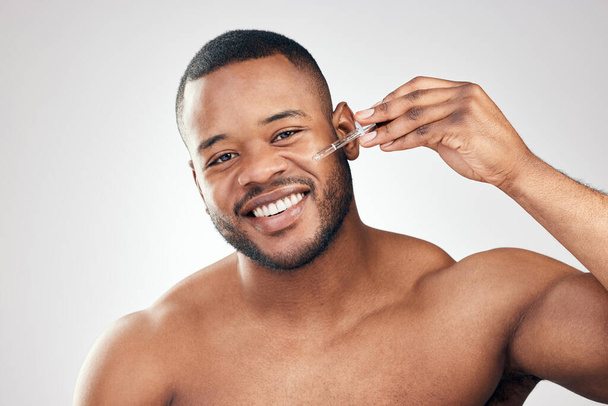 A face that is well hydrated is youthful. Studio portrait of a handsome young man applying serum to his face with a dropper against a white background. - Photo, Image