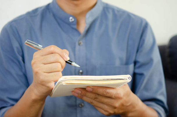 Homme d'affaires tenant un stylo et un carnet pour prendre des notes et planifier des idées. - Photo, image