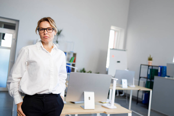 Γυναικείο αφεντικό με λευκό πουκάμισο και γυαλιά στο γραφείο - Φωτογραφία, εικόνα