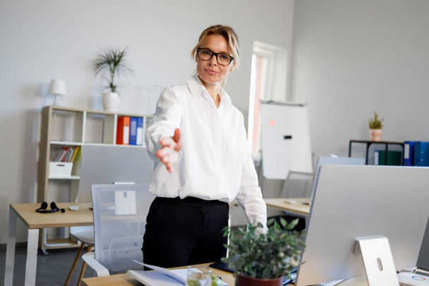 Geschäftsfrau mittleren Alters im Büro streckt ihre Hand für einen Händedruck aus - Foto, Bild