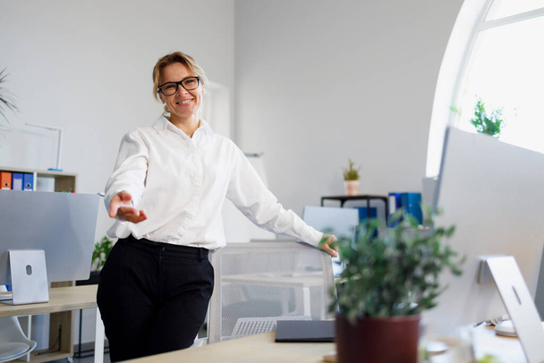 Friendly female office worker in glasses and formal wear showing welcome gesture - Фото, зображення