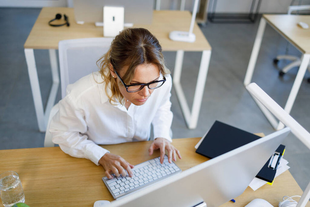 Middle aged business woman is concentrated on working at a computer - Foto, Imagem
