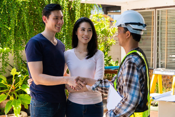Happy homeowner stand in front of contractor and shake hand, handyman holding clipboard and after checking details before renovations home, house improvement interior, Interior design - Foto, Imagen