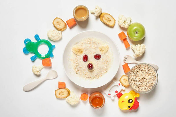 Homemade organic baby porridge and a pile of toys, vegetables an - 写真・画像