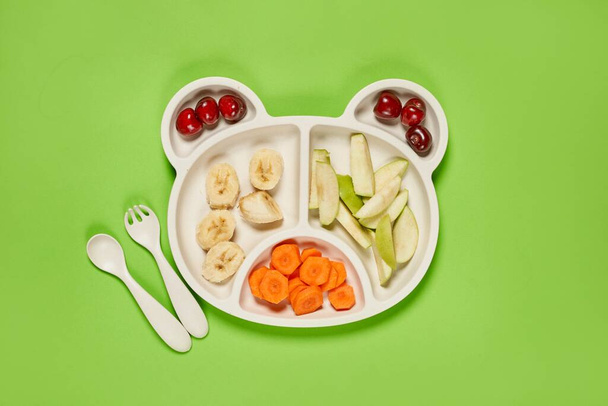 Fresh cherries, apple, banana and carrot slices on bear-shaped b - 写真・画像