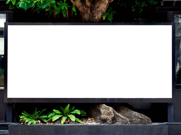 White blank space on a street billboard near the big tree and building. Outdoor empty horizontal frame mockup on the street for advertising. - Photo, Image